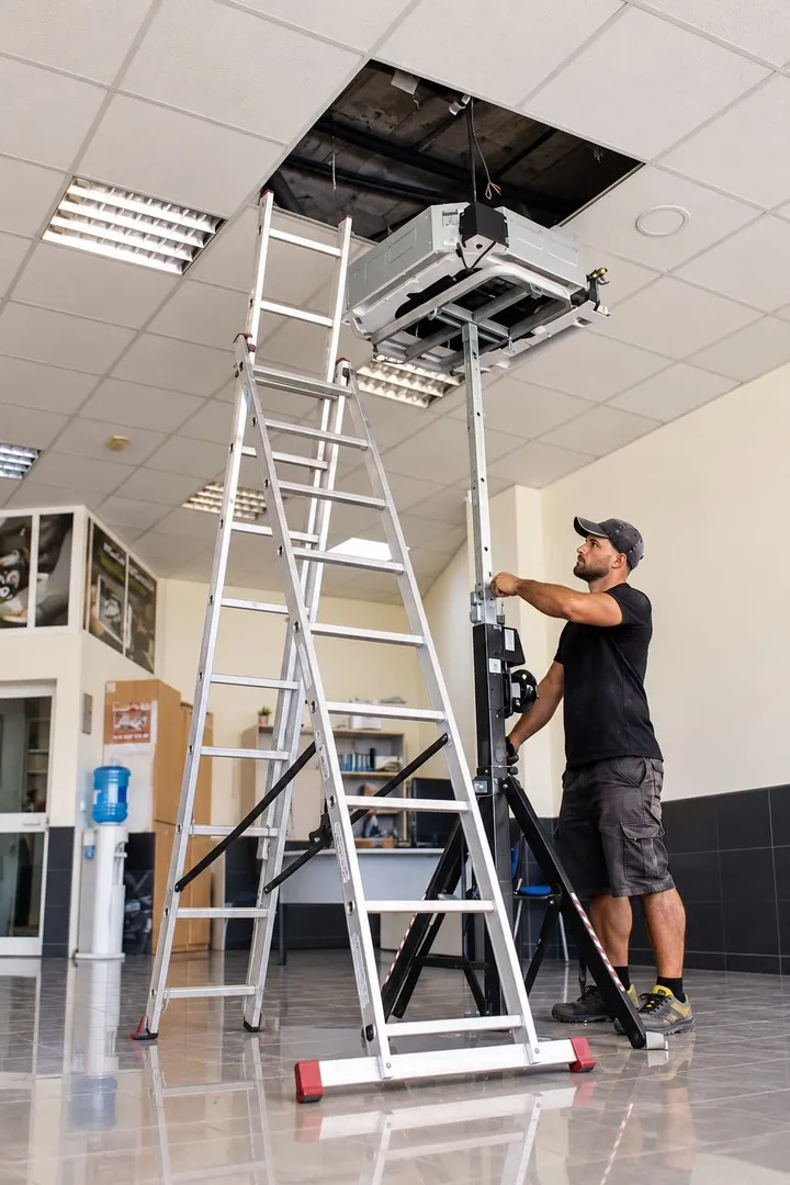 Commercial ceiling cassette air conditioning installation using a hoist and ladder in Málaga province